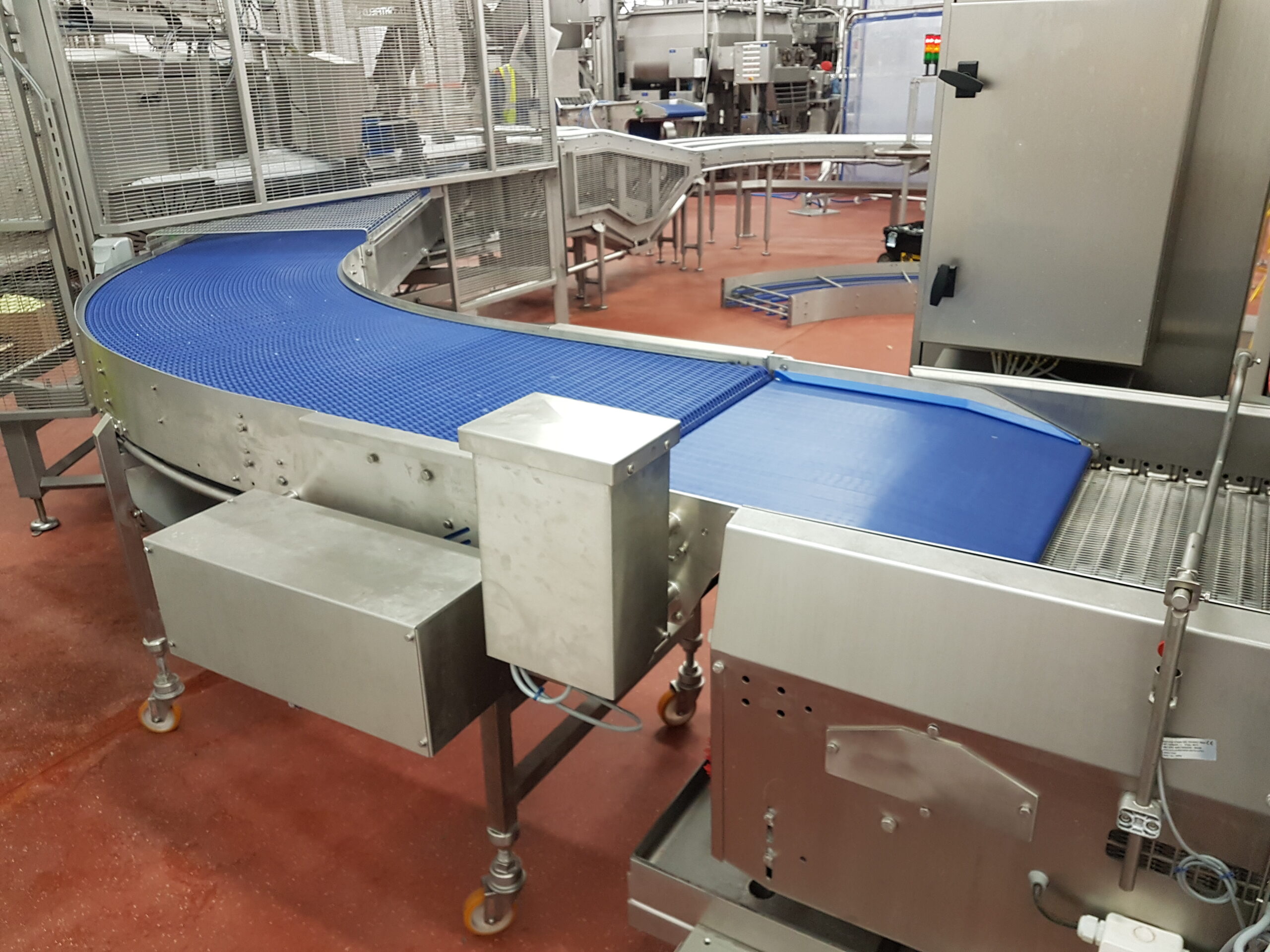 Radius conveyor with transfer belt with tight nose transfer and underslung drive freezer in feed Wrightfield